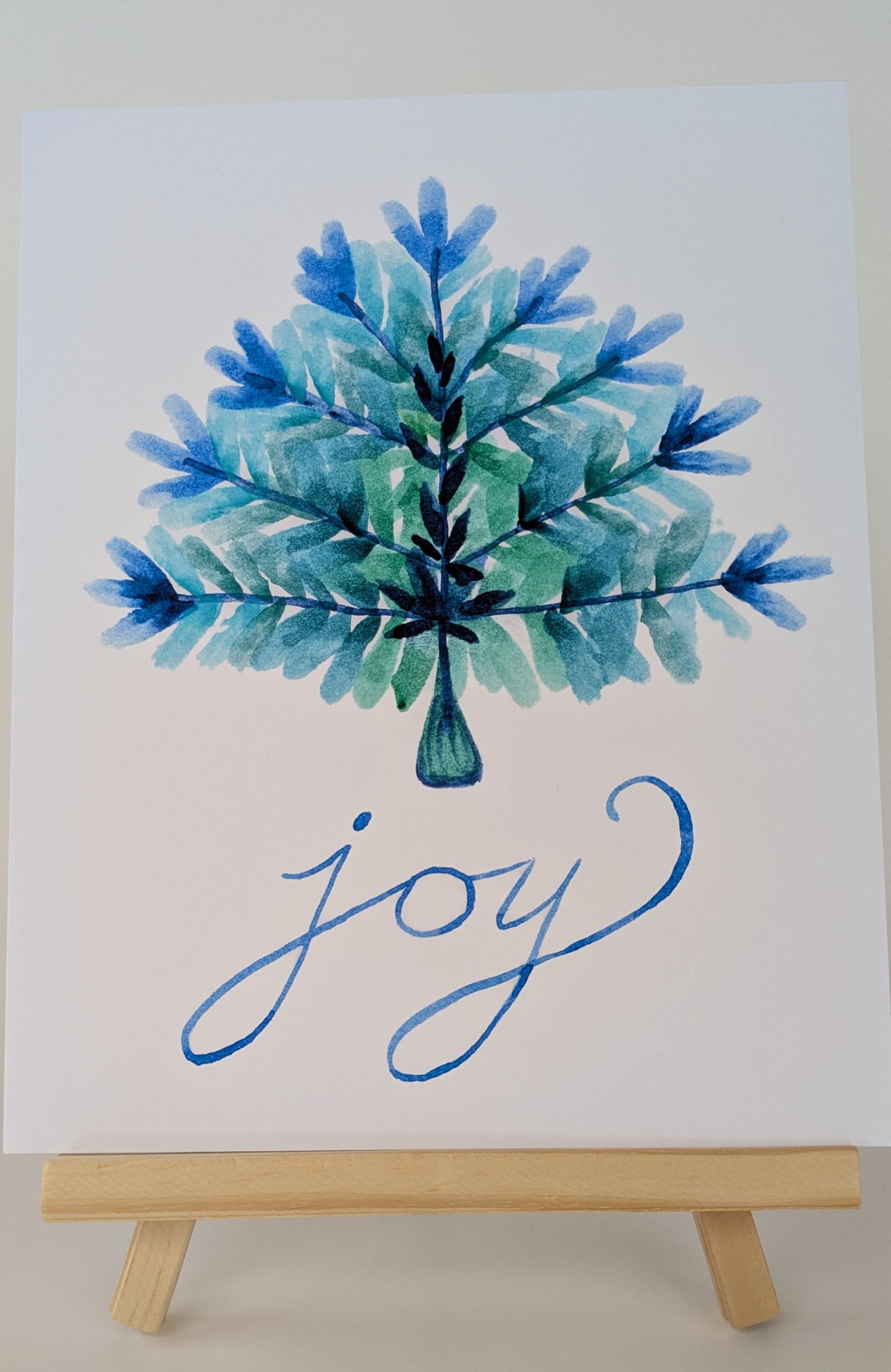 Watercolor painting of a Christmas tree with 'joy' text on a white background